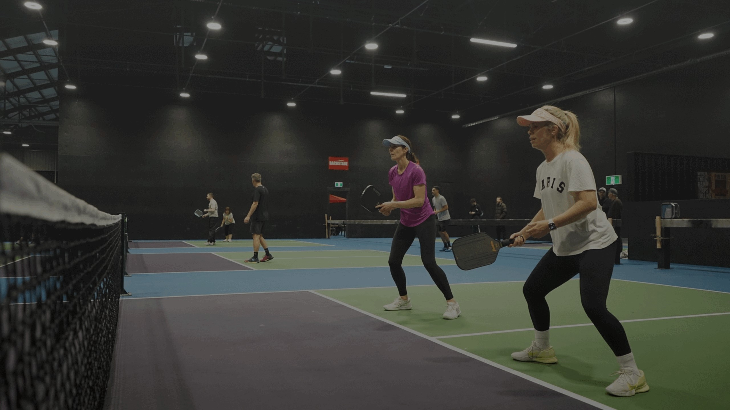 Players on indoor pickleball courts at The Shed